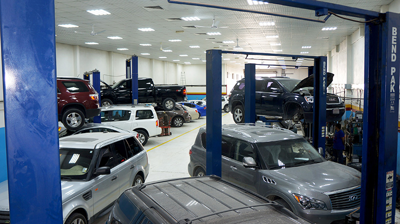 Wide view of workshop with cars on twin-post lifts